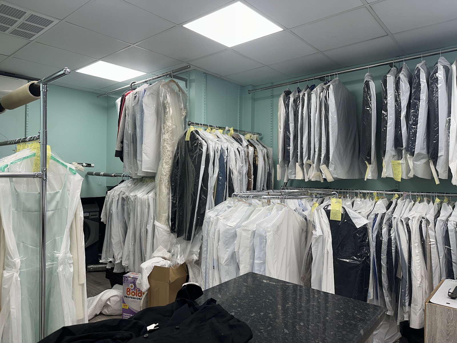 Interior racks of finished shirts and garments wrapped in clear plastic at Smartline Dry Cleaners, photographed by Canton Yip